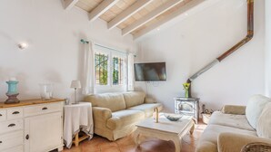 Una sala de estar con sofá, mesa de centro, televisor, chimenea y ventana con cortinas.