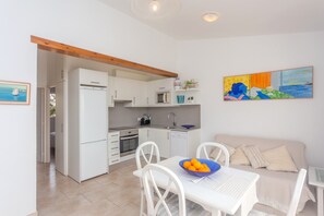 Une cuisine moderne avec des meubles blancs, une table à manger avec des chaises et un tableau accroché au mur.