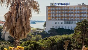 A building with 'GLOBALES' signage, surrounded by greenery and a body of water. - Apartment Cala en Forcat 36 with Balcony & Shared Pool (Cala en Blanes)