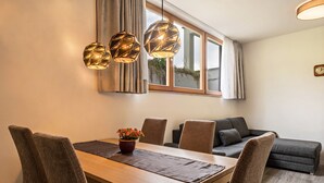 Ein Essbereich mit Holztisch, Stühlen, einer Zimmerpflanze und einer Couch.