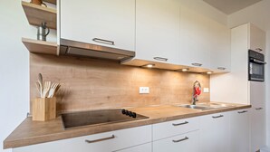 Eine moderne Küche mit weißen Schränken, einer Holz Arbeitsplatte, einer Edelstahl-Spüle und einem eingebauten Backofen.