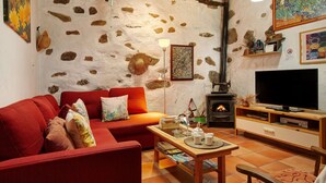 Ein gemütliches Wohnzimmer mit einer roten Couch, einem Holztisch, einem Fernseher und einem Kamin.
