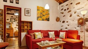 Ein gemütliches Wohnzimmer mit einem roten Sofa, einem Holztisch mit Tee-Service und einer Steinwand.