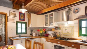 Eine Küche mit Holzschränken, einem Gasherd, einer Spüle und einem Esstisch mit Stühlen.