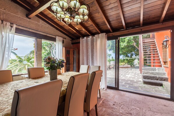 A dining area with a table, chairs, a chandelier, and a view of a staircase and outdoor area.