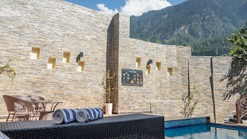 Una piscina al aire libre, sombrillas, sillones reclinables de piscina