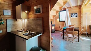 A cozy cabin interior with a kitchen area, dining space, and a fireplace.