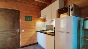 A compact kitchen with wooden walls, a white refrigerator, a stove, and a small countertop.