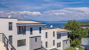 A modern building with multiple balconies overlooking a coastal area. - Apartment LAGANINI I near the beach (Njivice)