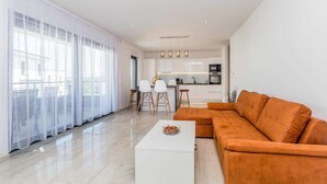 Una sala de estar moderna con un sofá, una mesa de centro y una cocina al fondo.