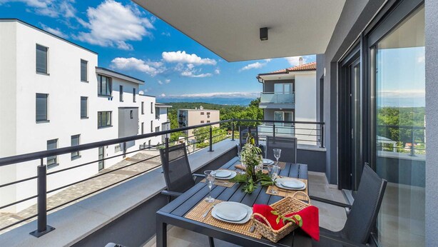 Un balcón con una mesa lista para comer, con vista a una zona residencial y edificios modernos.