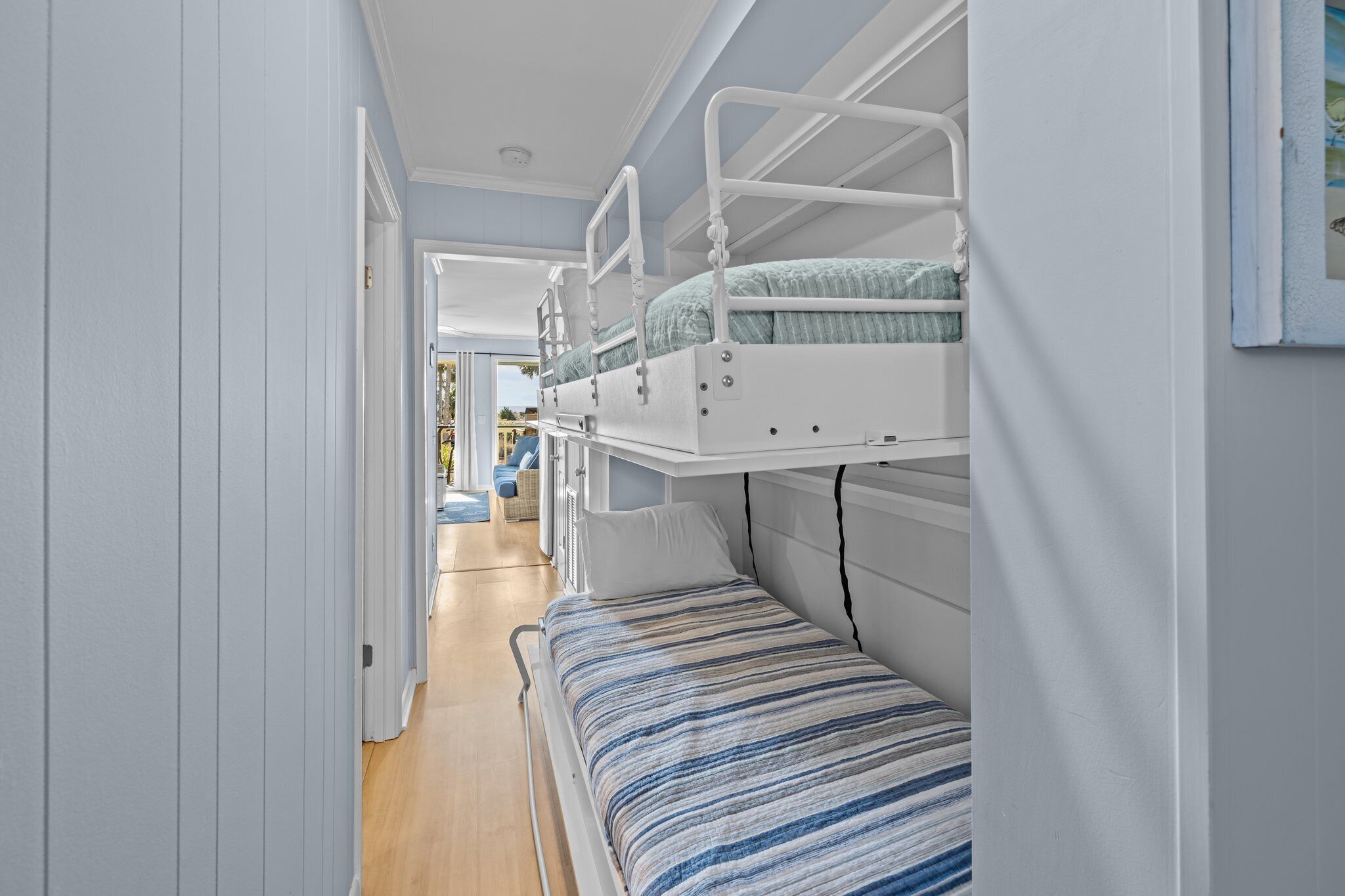 A narrow hallway with a bunk bed on the right and a single bed on the left.
