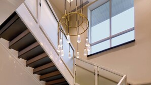 A modern staircase with glass railings and a chandelier. - Courtyard by Marriott Atlanta Duluth Downtown (Duluth)