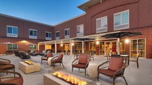 A brick building with outdoor seating, fire pits, and umbrellas. - Courtyard by Marriott Atlanta Duluth Downtown (Duluth)