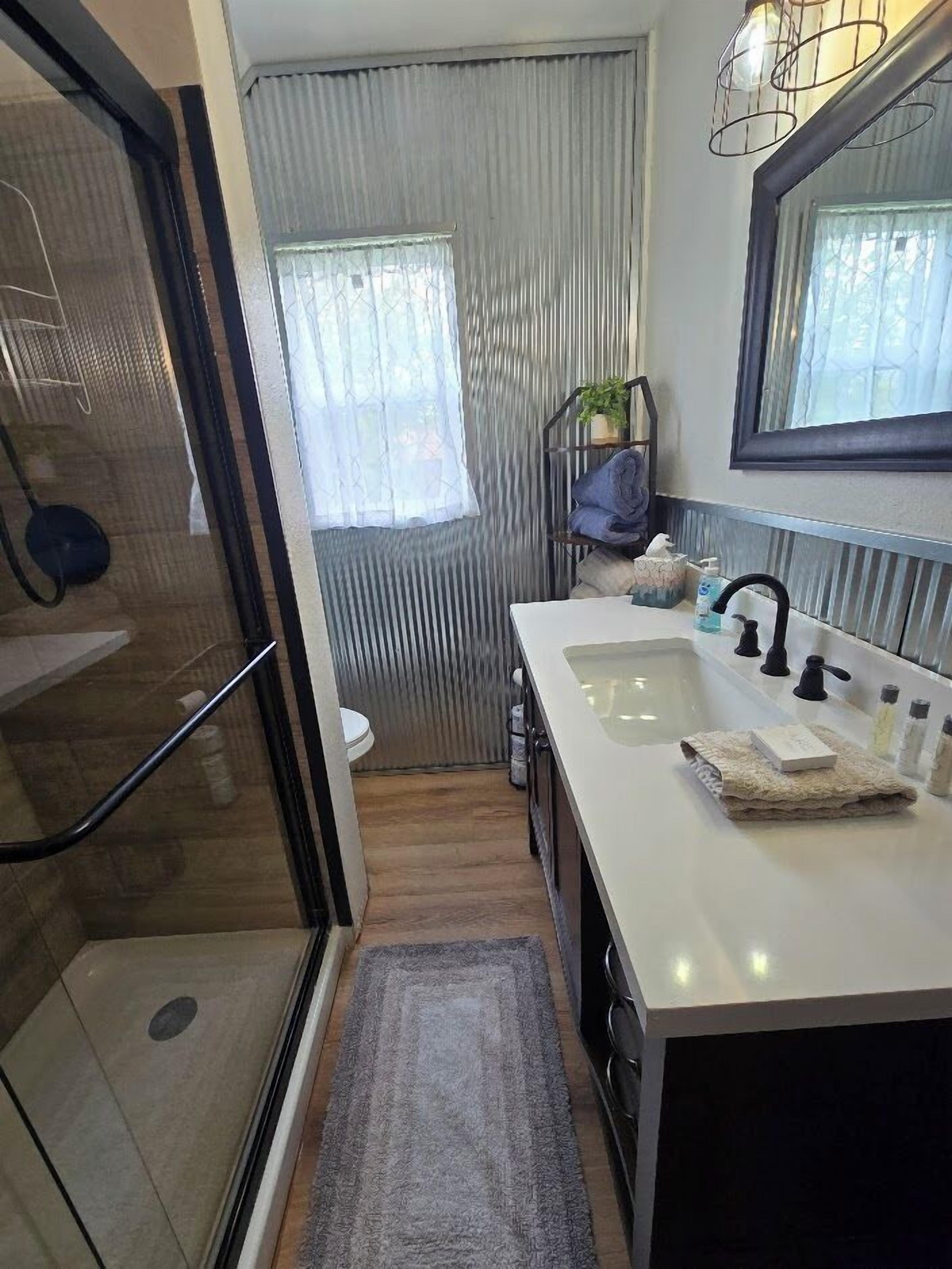 Une petite salle de bain avec une douche en verre, un lavabo blanc et un miroir au-dessus.