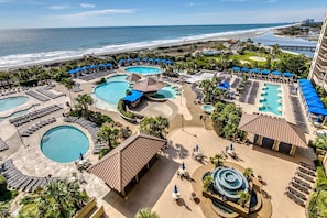 Relax by the central pool with its unique spiral design, surrounded by lush greenery and ocean views.