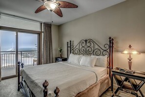 A hotel room with a large bed, a ceiling fan, a nightstand with a lamp, and a view of the beach through the window. - Gorgeous 16th Floor Oceanfront Condo at North Beach Resort & Villas - $300 FREE Activities Daily! (North Myrtle Beach)