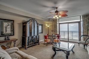 Relax in this stylish living room with a sofa, coffee table, and dining table for four, plus a large window with ocean views.