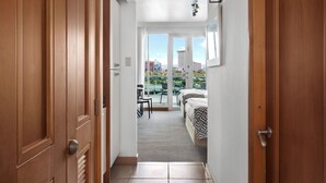 Un couloir menant à un balcon où se trouvent un lit et une table.