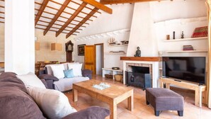 A cozy living room with a fireplace, a television, and a chessboard on a wooden table. - Finca Na Bona · Finca Na Bona. Perfect location. Menorca (Mahón)