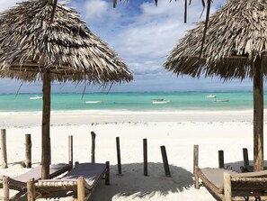Praia particular, areia branca, espreguiçadeiras, guarda-sóis 