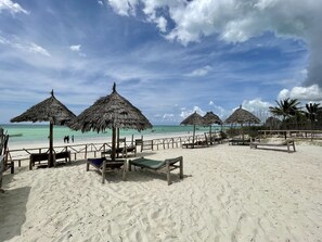 Praia particular, areia branca, espreguiçadeiras, guarda-sóis 