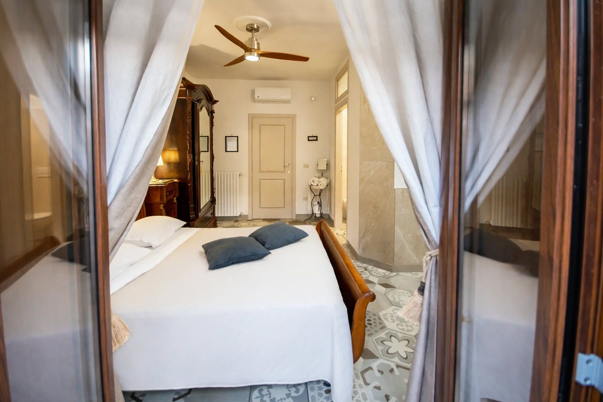 Une chambre à coucher avec un lit, un ventilateur de plafond, un radiateur et une porte.