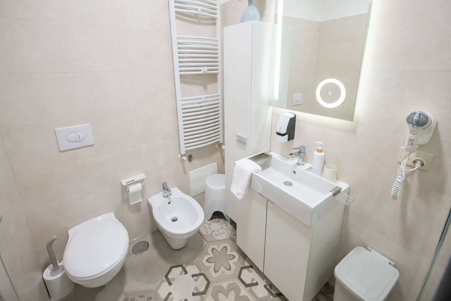 Une salle de bain moderne équipée de toilettes, d’un bidet, d’un lavabo et d’un sèche-cheveux.