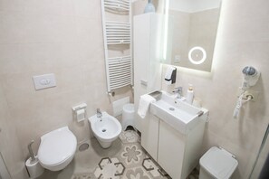 Un baño moderno con inodoro, bidé, lavabo y un secador de pelo.