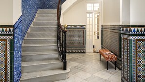 A grand staircase with intricate blue and white tile designs, leading to an upper floor. - Villa Alfonso, Luxurious restored palace house next to Plaza de España. (Sevilla)