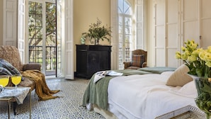 A bedroom with two beds, a dresser, and a window with a view of trees. - Villa Alfonso, Luxurious restored palace house next to Plaza de España. (Sevilla)