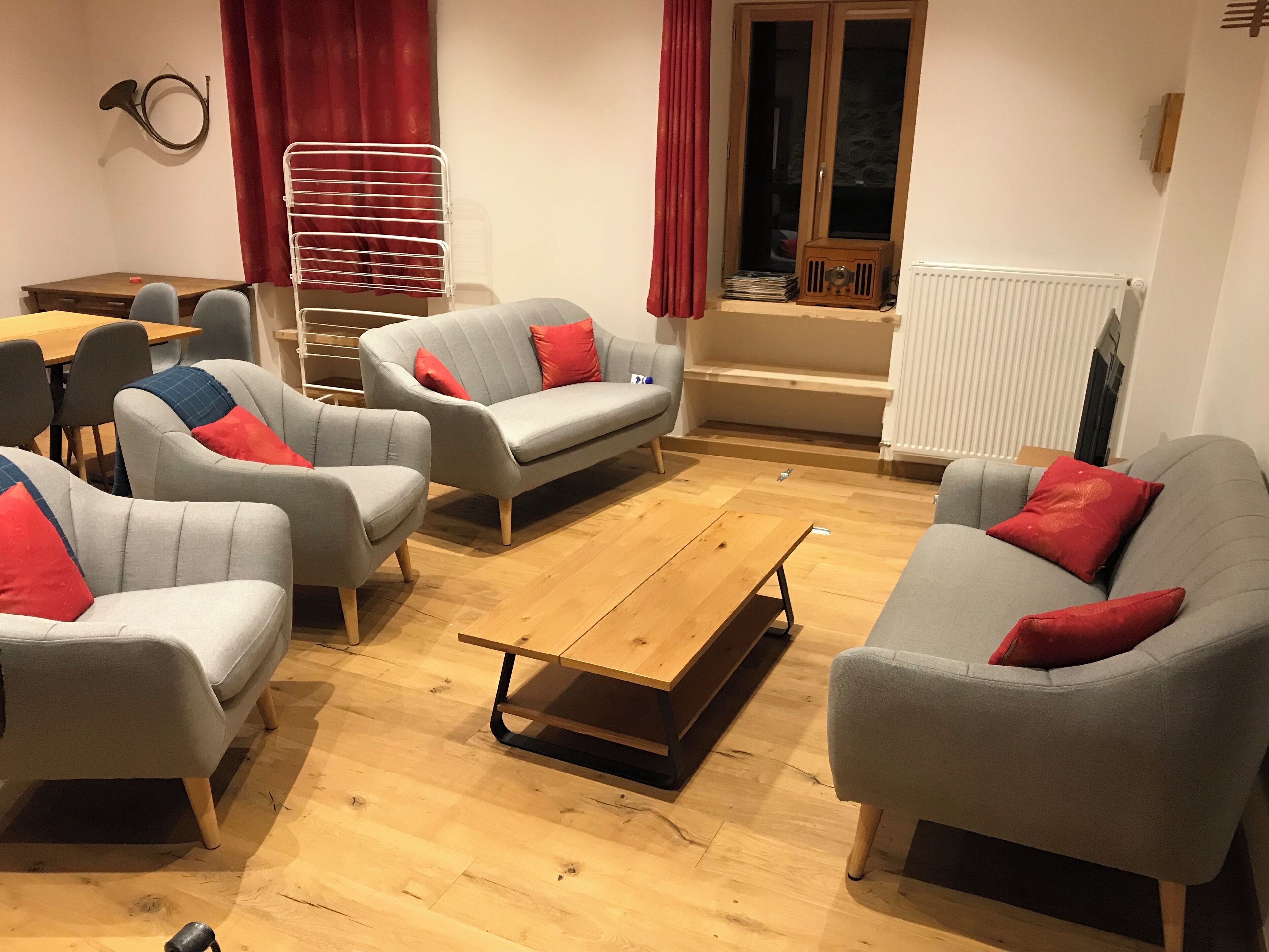 Un salón con sofás y sillones grises, una mesa de centro de madera y un radiador.