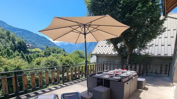 Eine Terrassengruppe mit Tisch, Stühlen und einem großen Sonnenschirm.