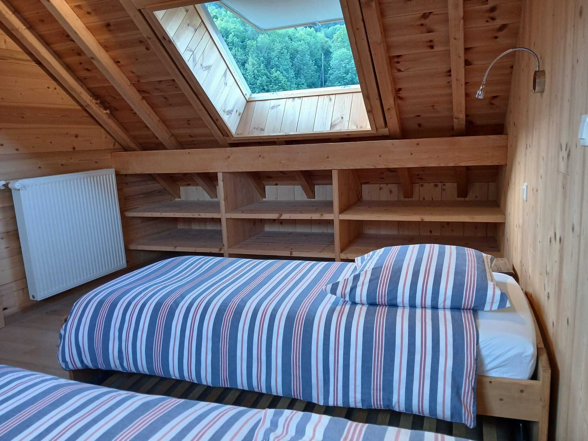 Eine Holzhütte mit einem Oberlicht, einem Bett mit gestreifter Bettwäsche und einem weißen Heizkörper.