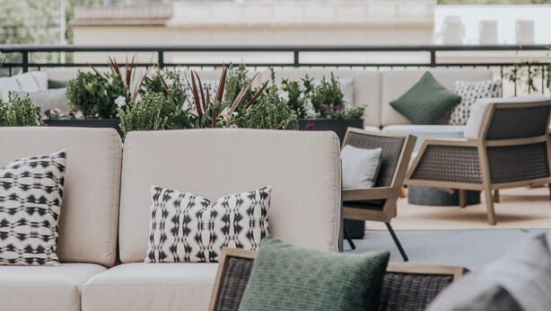 A rooftop terrace with a sofa and chairs, city skyline in the background, and greenery overhead. - Bellyard, West Midtown Atlanta, a Tribute Portfolio Hotel (Atlanta)