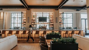 A modern bar area with a long counter, multiple bar stools, and a variety of bottles and glasses. - Bellyard, West Midtown Atlanta, a Tribute Portfolio Hotel (Atlanta)