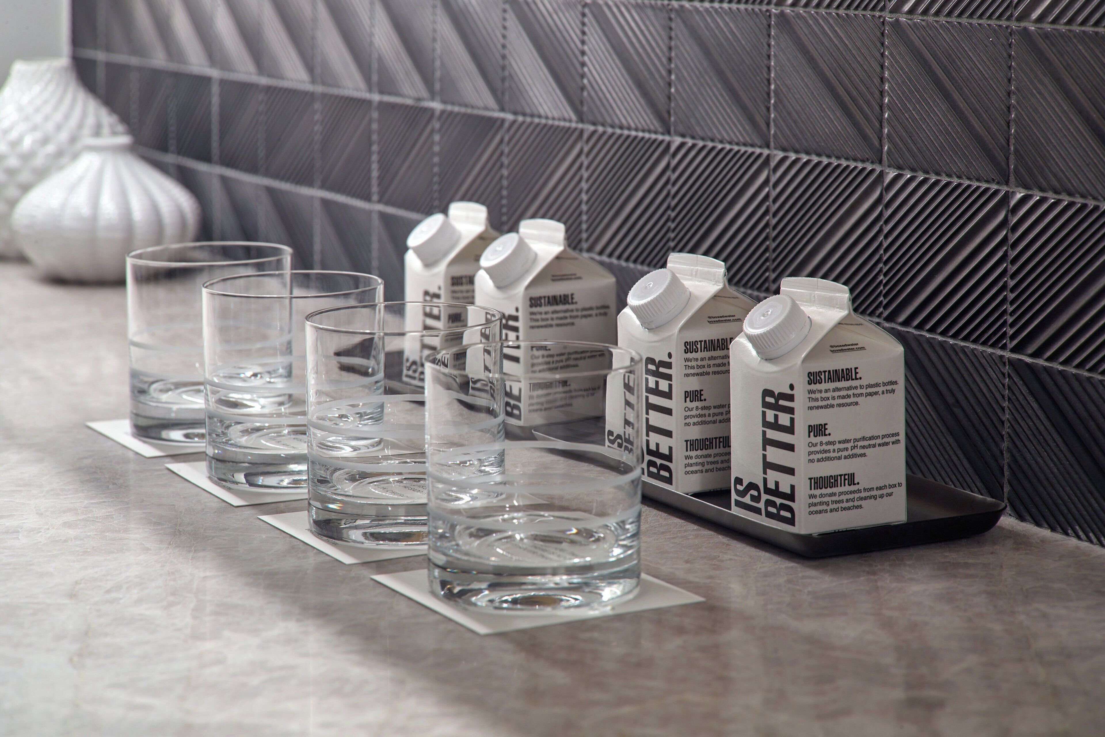 A water dispenser with multiple bottles and glasses on a countertop.