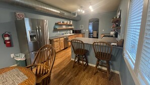 Een moderne keuken met houten kastjes, roestvrijstalen apparatuur en een centraal eiland met barkrukken.