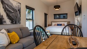 A modern bedroom with a large bed, a sofa, and a dining table.
