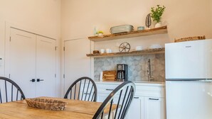 A compact kitchen with white cabinets, a coffee maker, and a refrigerator.
