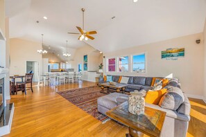 Amplia sala de estar con sofá gris, mesa de centro de madera y vistas al área de la cocina y comedor.