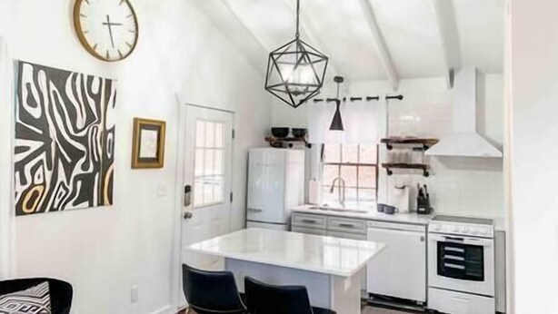 A modern kitchen with white cabinetry, a central island, and a hanging light fixture. - Mountain Retreat: Virginia Foothills (Charlottesville)