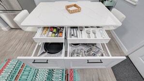 Una cocina moderna con armarios blancos, encimera de mármol y organizador de cajones empotrado.