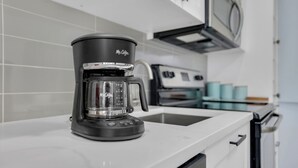 Una cafetera Mr. Coffee negra sobre una encimera de cocina blanca.