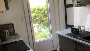 Eine Küche mit Schachbrettboden, einem Fenster mit Blick auf Grünflächen und einer Spüle.