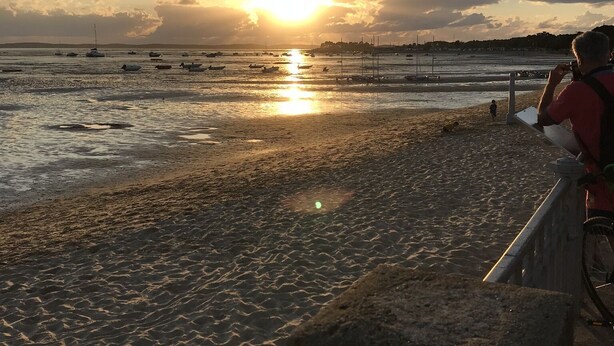 Ein Strand mit Booten und einem Sonnenuntergang.