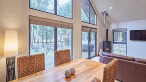 Una habitación amplia con una gran mesa de comedor de madera, sillas tejidas, un sofá de cuero y una chimenea.