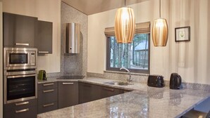 Una cocina moderna con encimeras de granito, electrodomésticos de acero inoxidable e iluminación colgante.