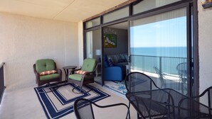 A balcony with wicker chairs, a blue sofa, and a small table. - Enjoy beautiful oceanfront views of the Ocean City coastline in this one bedroom, one bath condo located just a few steps from the beach! (Ocean City)