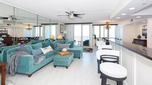 Ein geräumiges Wohnzimmer mit einer großen Sofagarnitur, einem Essbereich und einer Küche mit Bar.